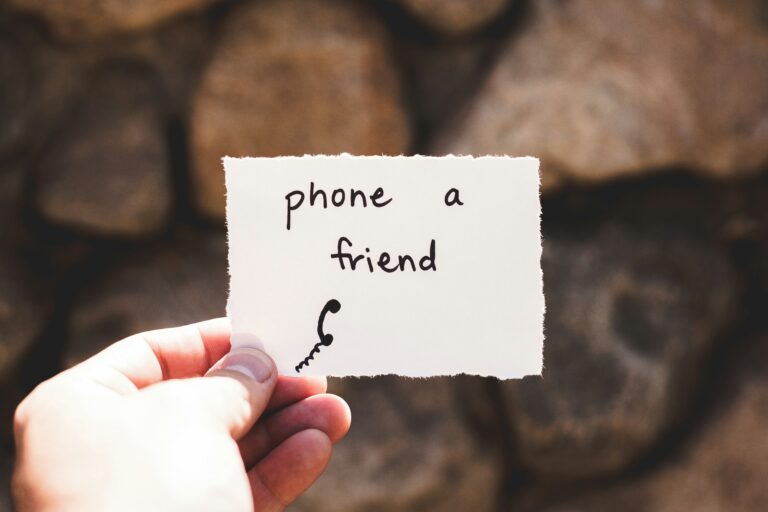 hand holding a piece of paper that says phone a friend-