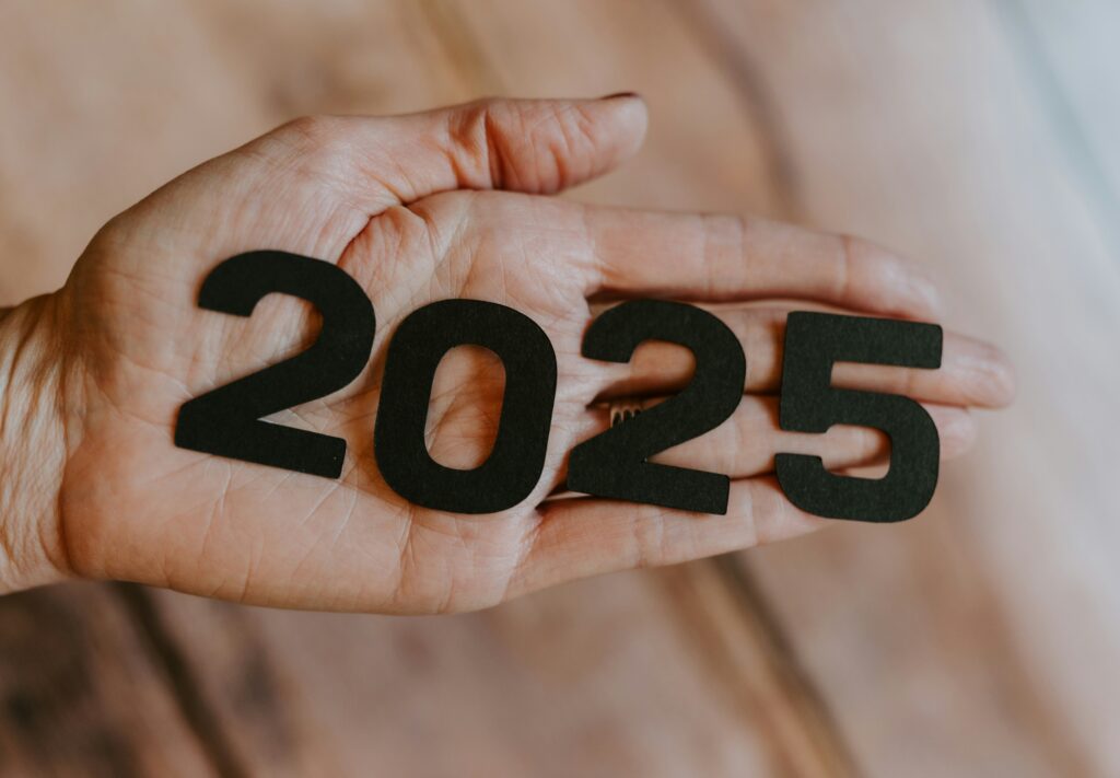 a hand holding black numbers that say 2025