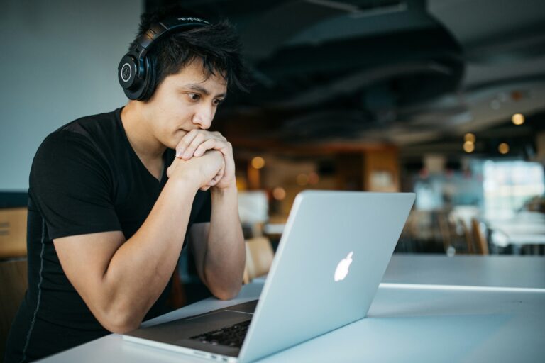 A male college student studying with headphones, focusing on college mental health.